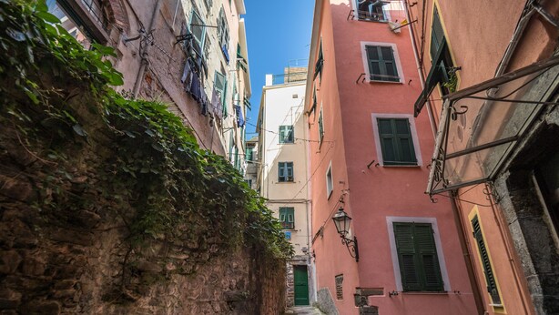 A narrow alleyway with stone walls and buildings on either side. There are steps leading up to a door at the end of the alley. - Camaella Luxury Studio (Vernazza)