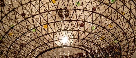 A spherical chandelier with a wireframe design and hanging crystal elements.