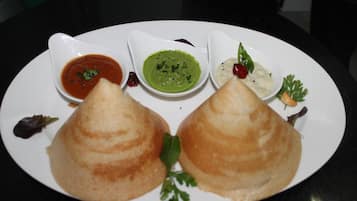 Un plato con dos porciones triangulares de comida, tres recipientes pequeños de salsas y algunos adornos.