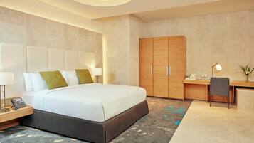 A modern hotel room with a large bed, a desk, and a wardrobe.