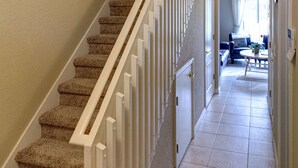 A carpeted staircase with white railings leading to a living area with a sofa and a coffee table.