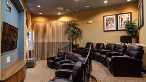A home theater with multiple leather recliners, a wooden bench, and a large plant.