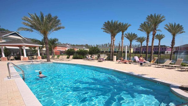 A swimming pool with lounge chairs and palm trees.