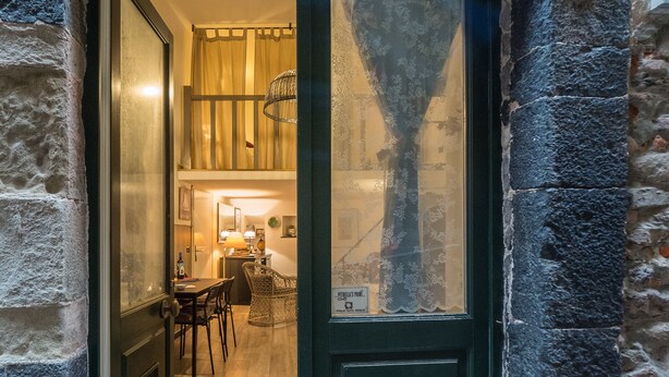 A dark wooden door with a glass panel, leading into a room with a wooden floor, a dining table, and chairs. - Petrella's Point Studio with AC (Vernazza)