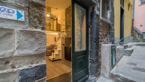 A stone building with a door leading to a room with a bed and a staircase. - Petrella's Point Studio with AC (Vernazza)
