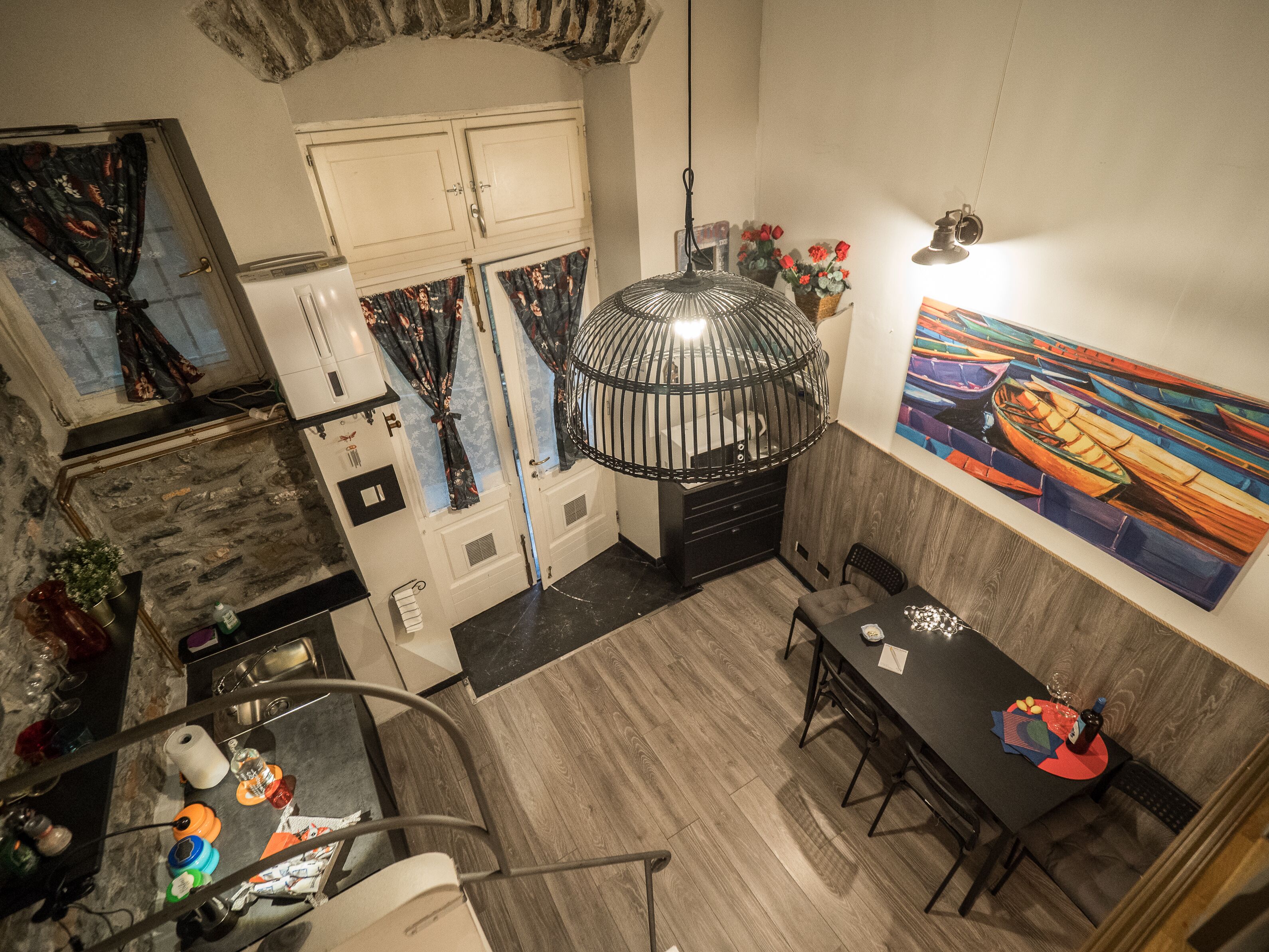 A modern kitchen with a stone wall, a dining area with a table and chairs, and a large painting on the wall.