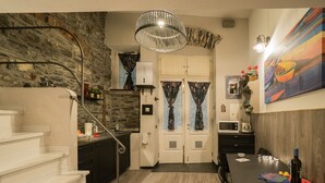 A modern kitchen with a stone wall, a dining area with a table and chairs, and a staircase leading to another level. - Petrella's Point Studio with AC (Vernazza)