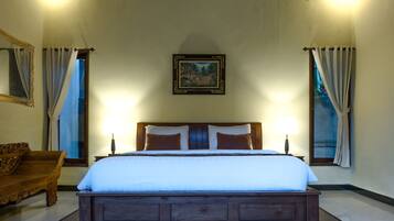 A neatly made bed with a wooden headboard, two bedside lamps, and a framed picture on the wall.