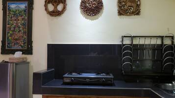A kitchen with a gas stove, a refrigerator, and decorative wall art.