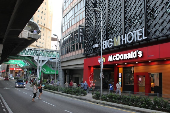 A McDonald's restaurant adjacent to the Big Hotel, with a pedestrian walkway and a green overhead structure.