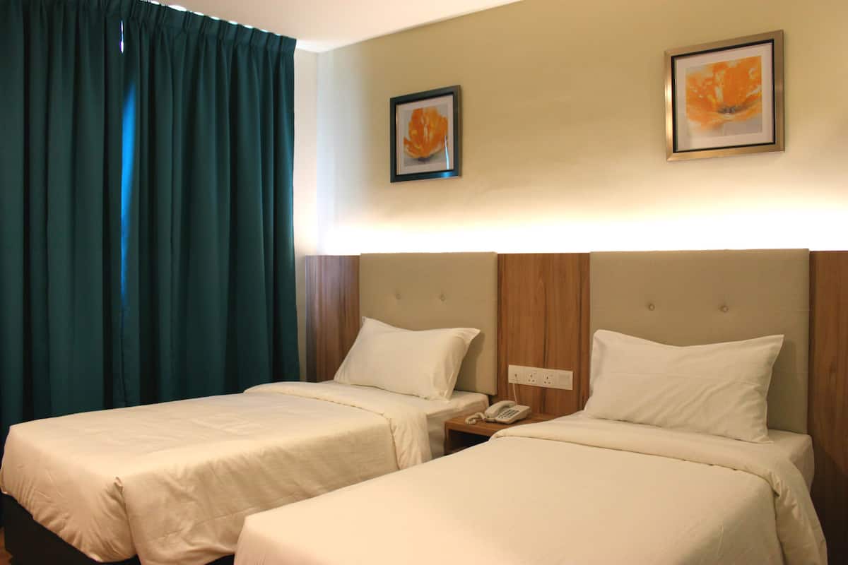 A hotel room with two beds, a telephone, and two framed pictures on the wall.