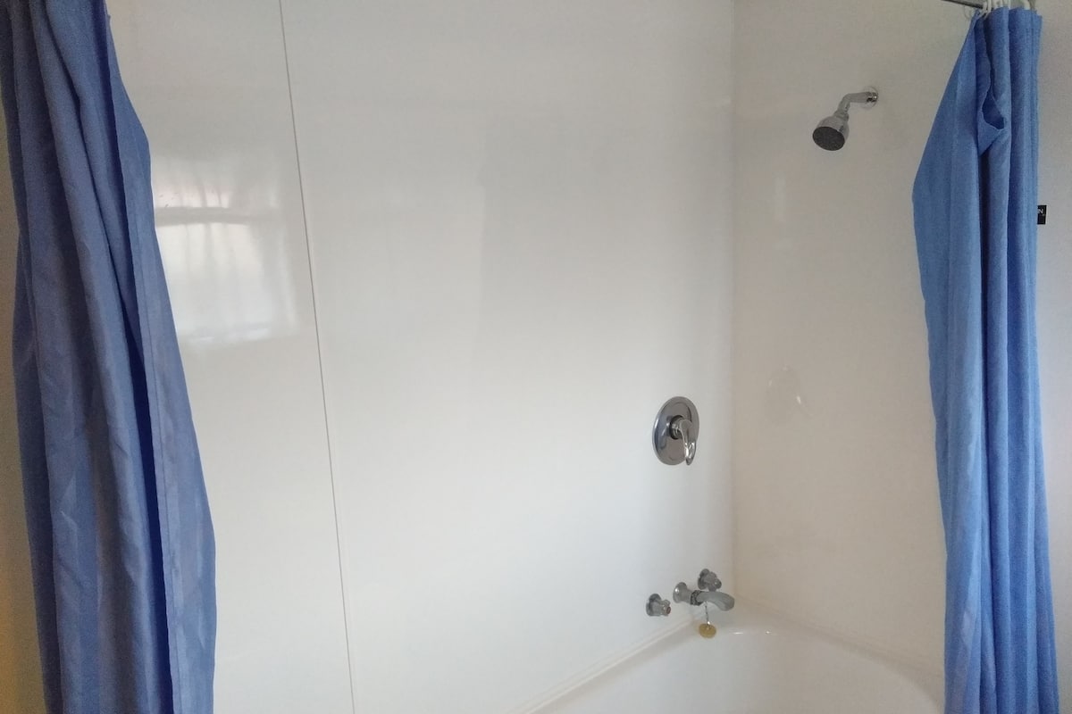 Een badkamer met een badkuip, douchekop en een kraan.