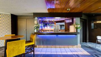 Eine Bar mit einer Theke, Barhocker und einer Wand mit Muster.