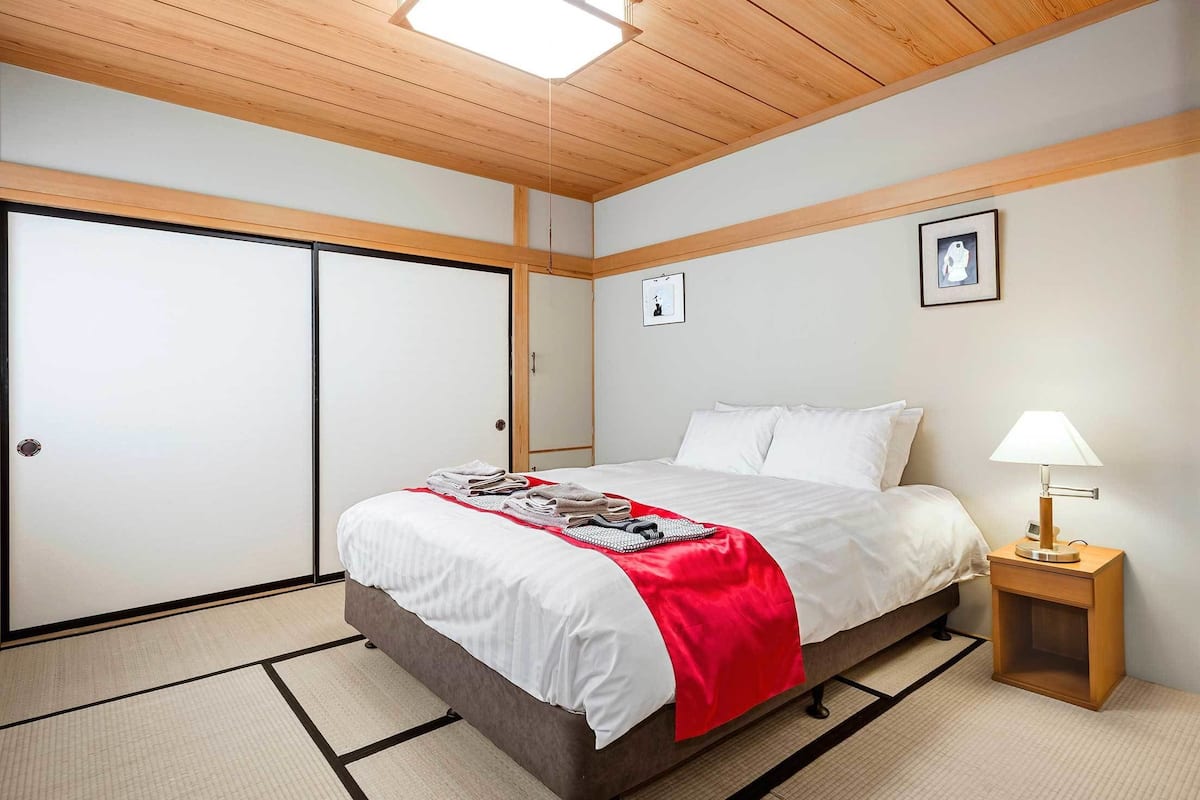 A hotel room with a bed, a nightstand with a lamp, a wardrobe, and a picture on the wall.