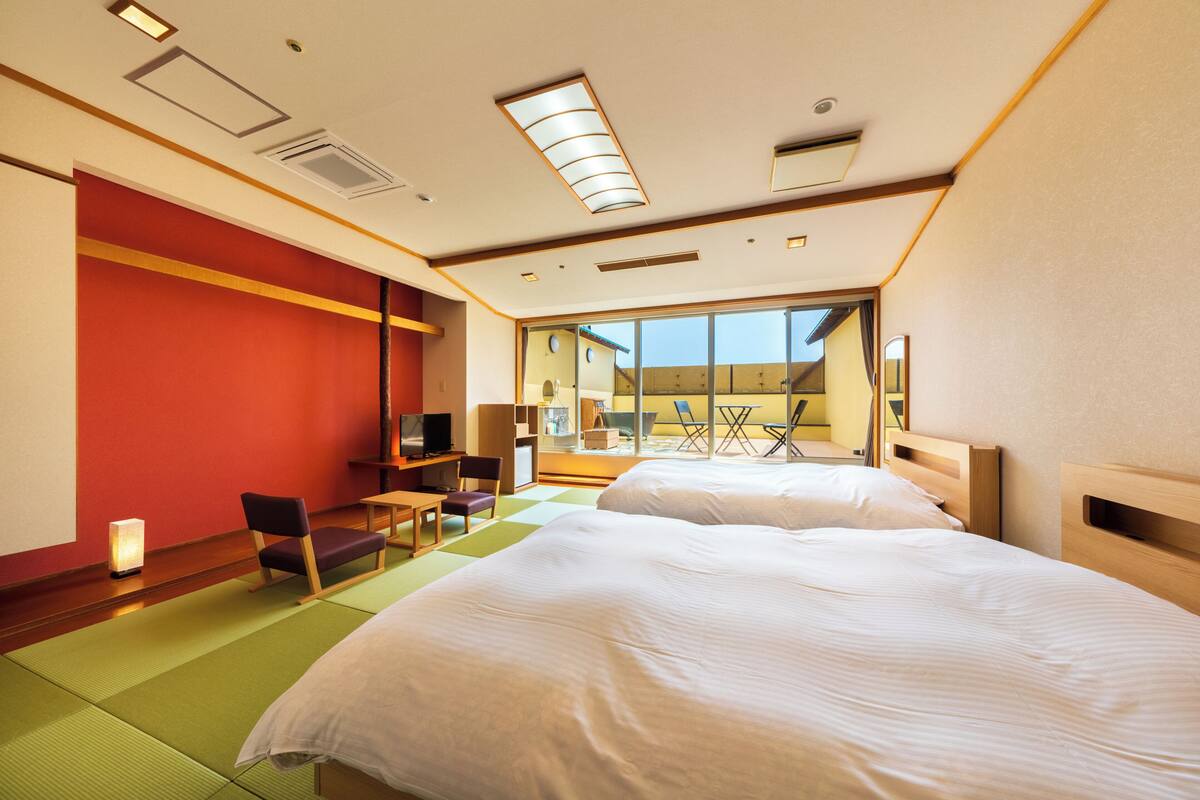 Une chambre d’hôtel avec un grand lit, un bureau, une chaise, une télévision et une vue sur l’extérieur.