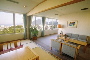 Amplia habitación con un gran ventanal con vista a la ciudad, un sofá, una mesa de comedor y una planta en maceta.
