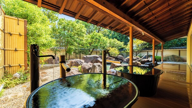 Un onsen japonais traditionnel, avec un toit en bois et des environs en pierre.