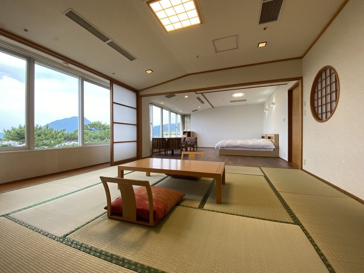Une pièce de style japonais traditionnel, avec un sol recouvert de tatamis, une petite table en bois et un lit.