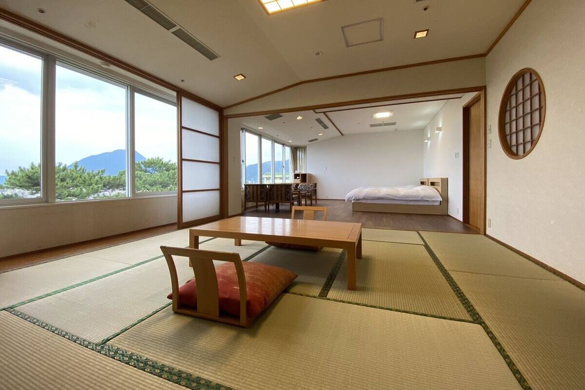 Una habitación tradicional japonesa con suelo de tatami, una mesa de madera baja y una cama.
