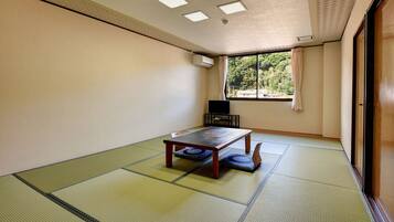 A traditional Japanese room with tatami flooring, a low table, and a TV.