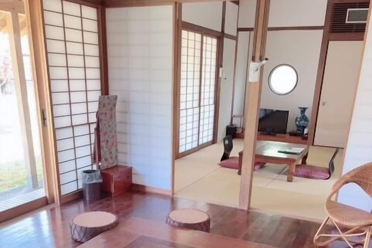 A traditional Japanese room with tatami flooring, a tatami mat table, a tea kettle, and a low wooden cabinet.