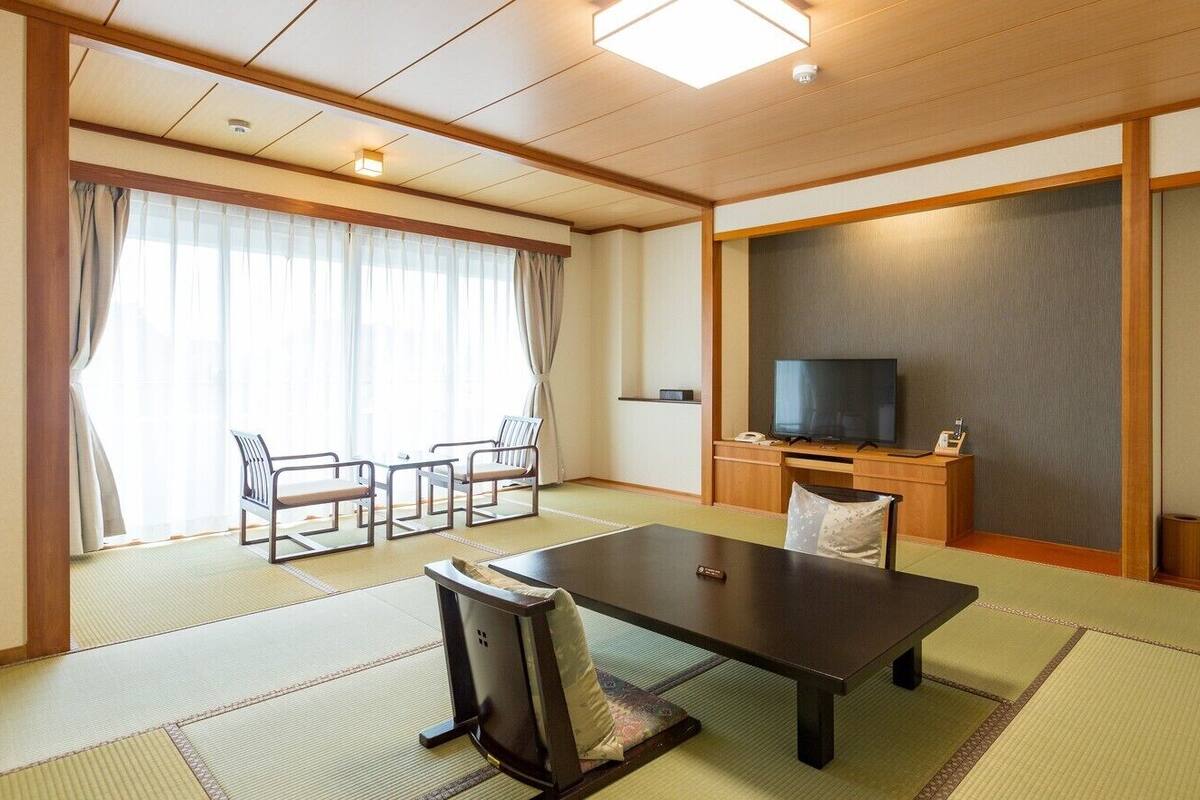 A traditional Japanese room with tatami flooring, a low table, a TV, and sliding doors.