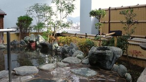 A traditional Japanese garden with a koi pond, rocks, bamboo fence, and various plants.