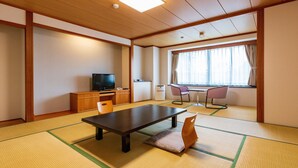A traditional Japanese room with tatami flooring, a television, a desk, and a window with curtains.
