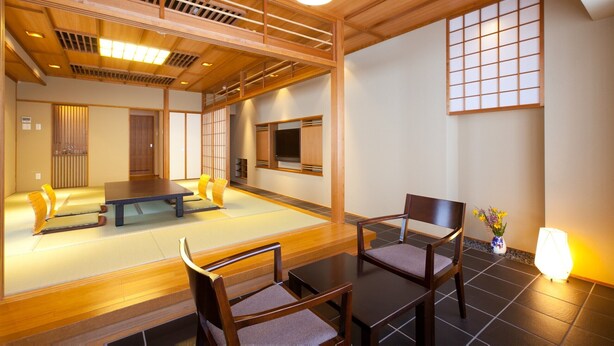 A traditional Japanese-style room with tatami flooring, a low table, and two chairs.