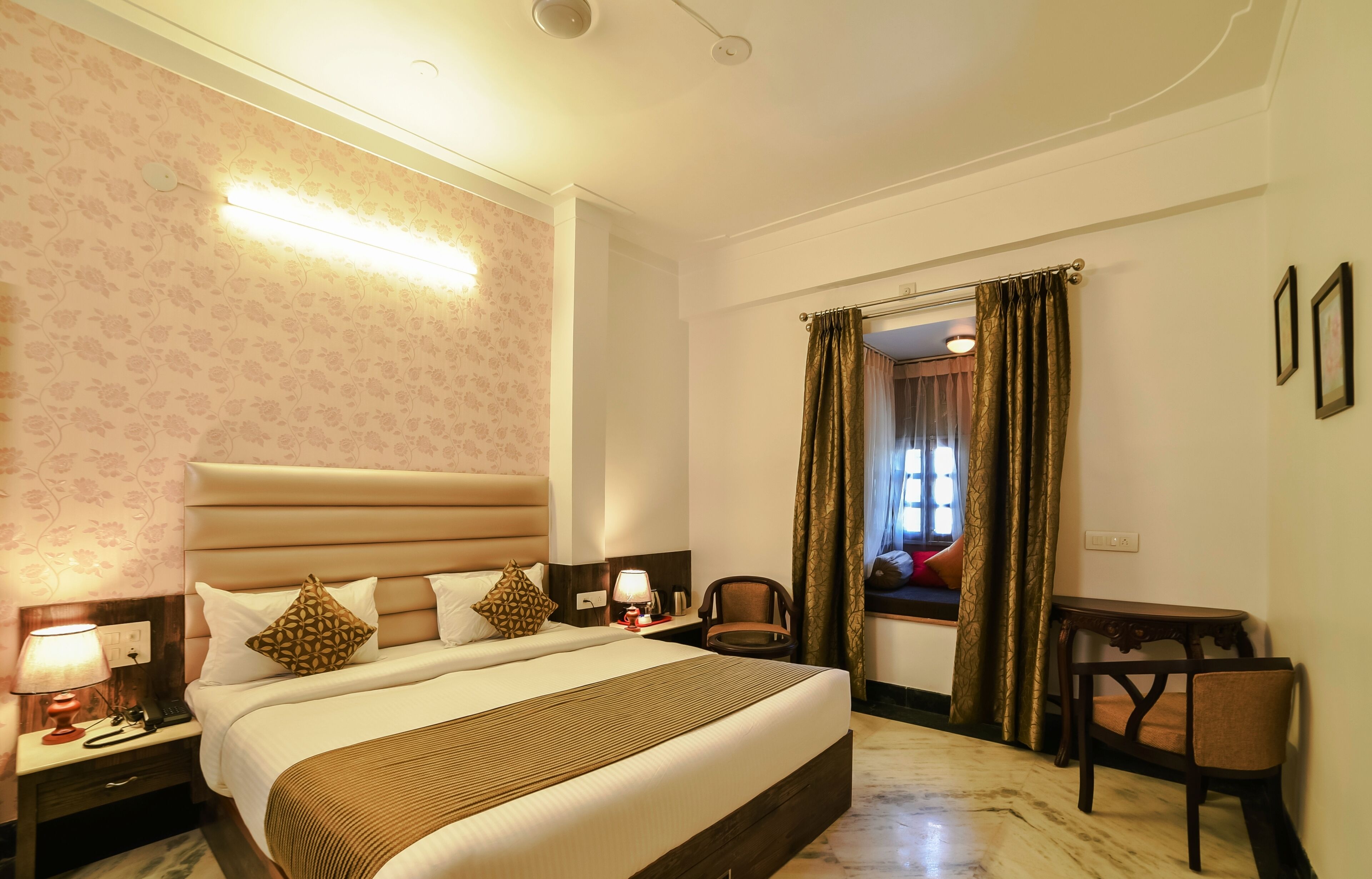 A hotel room with a large bed, bedside tables, a desk, and a chair.