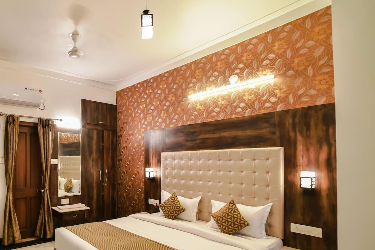 Une chambre bien éclairée, dotée d’un grand lit, d’une tête de lit en bois et d’un panneau décoratif mural.