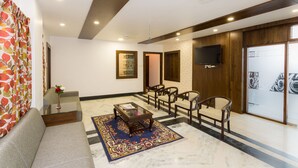 A modern living room with a sofa, a coffee table, and a TV mounted on the wall. - Hotel Castle Inn (Udaipur)