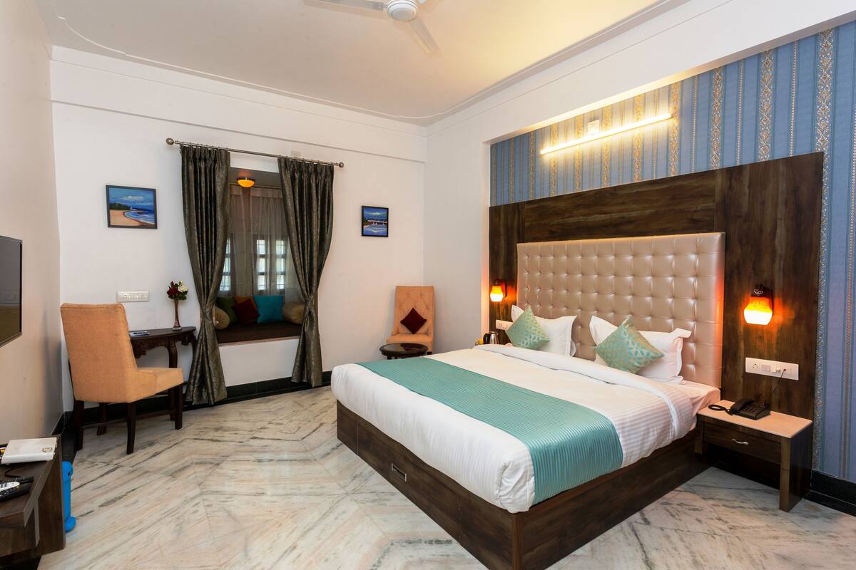 Une chambre d’hôtel avec un grand lit, un bureau, une chaise et un téléviseur.