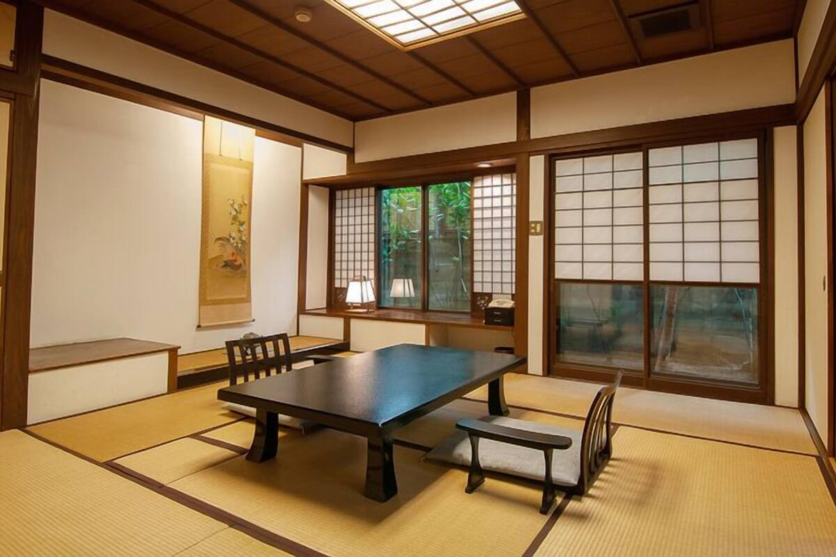 Une pièce de style japonais traditionnel, avec un sol recouvert de tatamis, une table basse et des portes coulissantes.