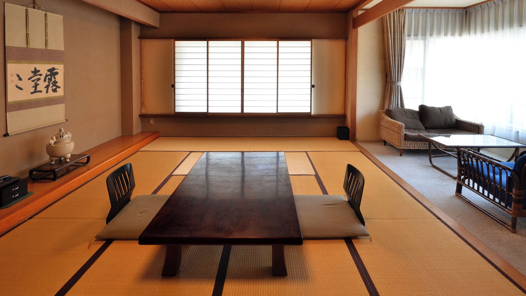 A traditional Japanese room with tatami flooring, a low table, and a sofa.