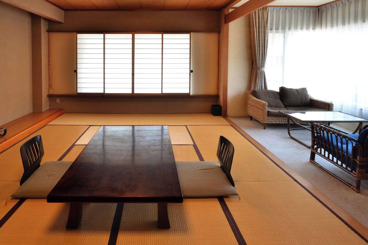 Une pièce de style japonais traditionnel, avec un sol recouvert de tatamis, une table basse et un canapé.