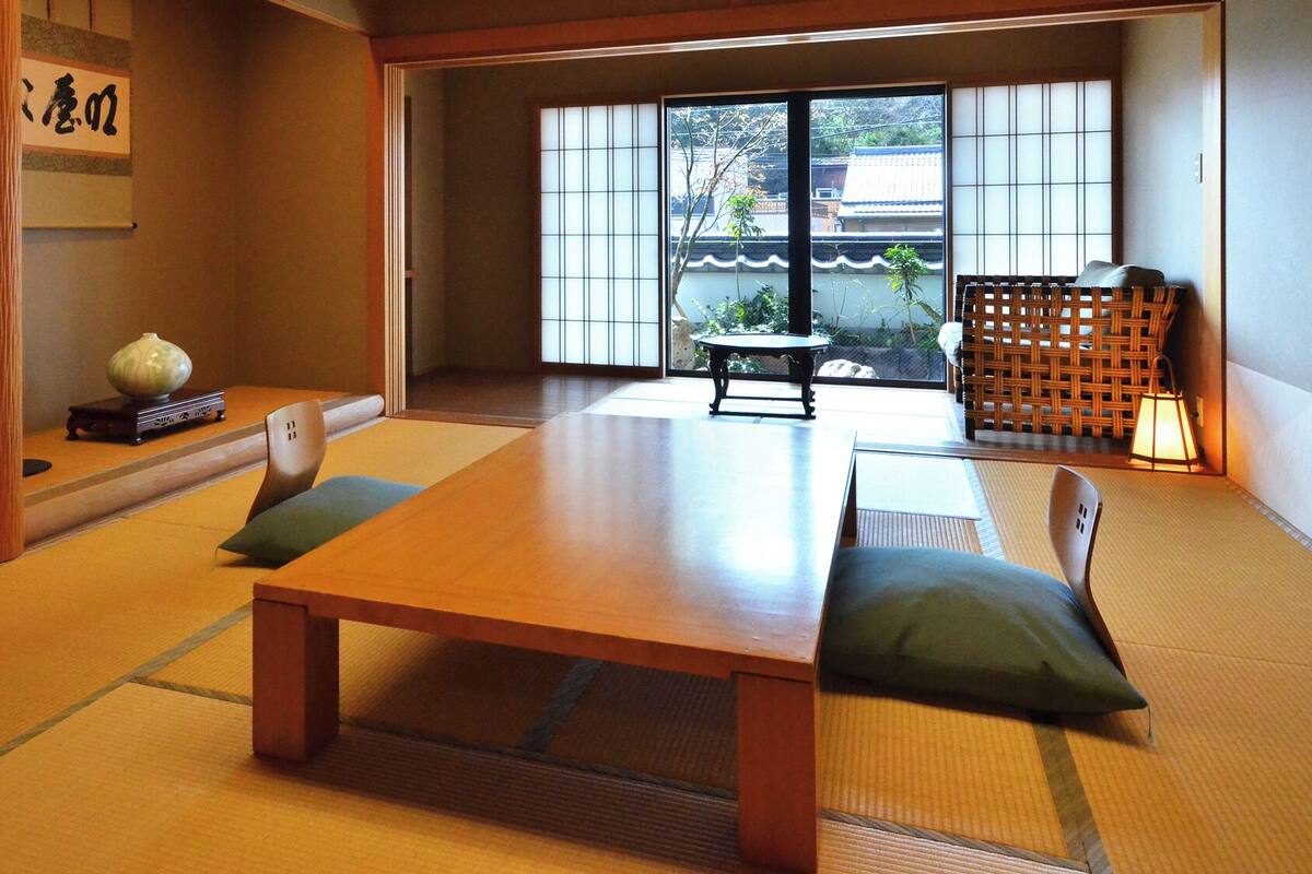 Une pièce de style japonais traditionnel, avec un sol recouvert de tatamis, une table basse et une vue à travers des panneaux coulissants.
