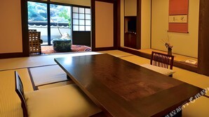 Une pièce traditionnelle japonaise avec un sol recouvert de tatamis, une petite table en bois, des tatamis, une porte coulissante et une vue sur un jardin.
