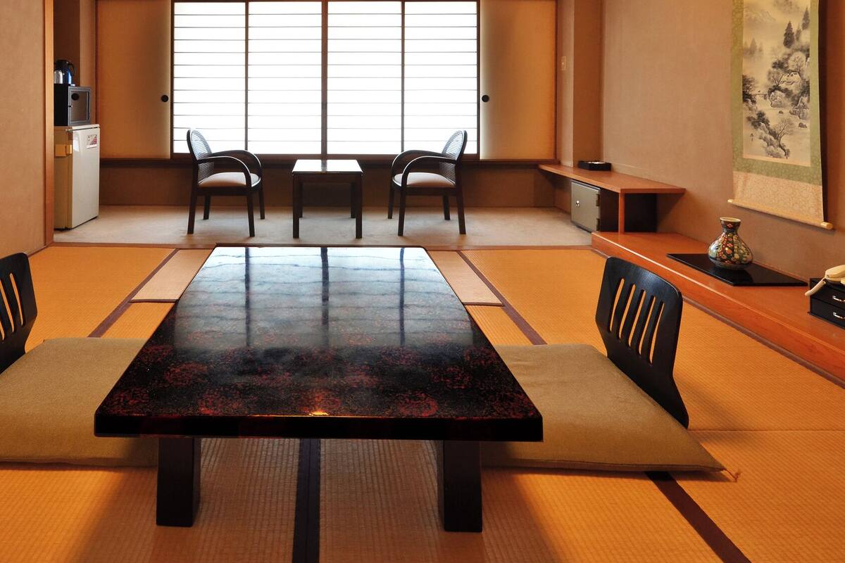 Une pièce de style japonais traditionnel, avec un sol recouvert de tatamis, une table basse et des chaises.