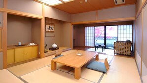 Une pièce de style japonais traditionnel, avec un sol recouvert de tatamis, une table en bois et une vue sur les cerisiers en fleurs, visible à travers de grandes fenêtres.