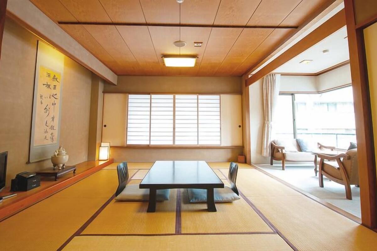 Une pièce de style japonais traditionnel, avec un sol recouvert de tatamis, une table basse et des portes coulissantes.