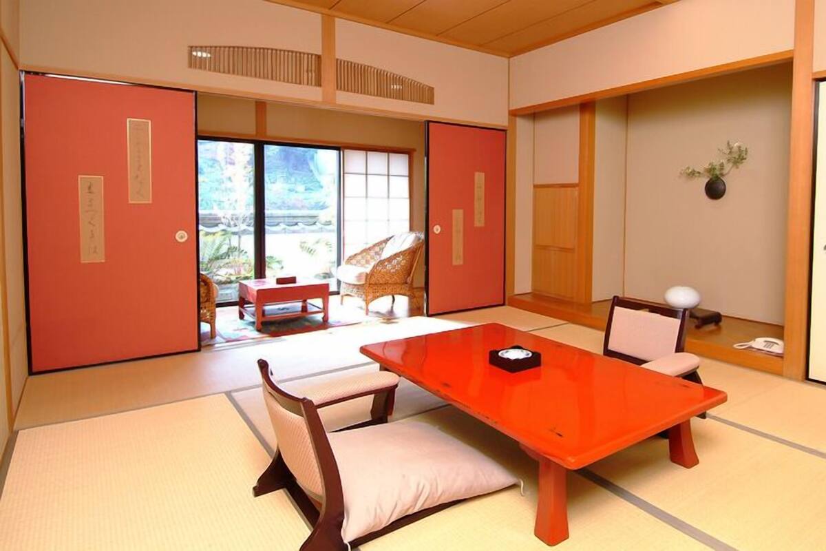 Une pièce de style japonais traditionnel, avec un sol recouvert de tatamis, une table basse et des portes coulissantes.