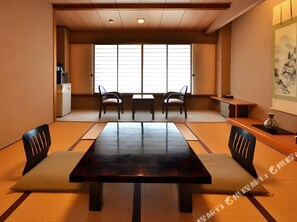 A traditional Japanese-style room with tatami flooring, a low table, two chairs, and a large window with shoji screens. - Yumotoso Toyokan (Takeo)