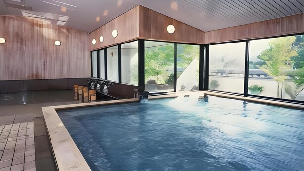Une piscine intérieure offrant une vue dégagée sur l’extérieur, un plafond en bois et un espace détente avec un barbecue.