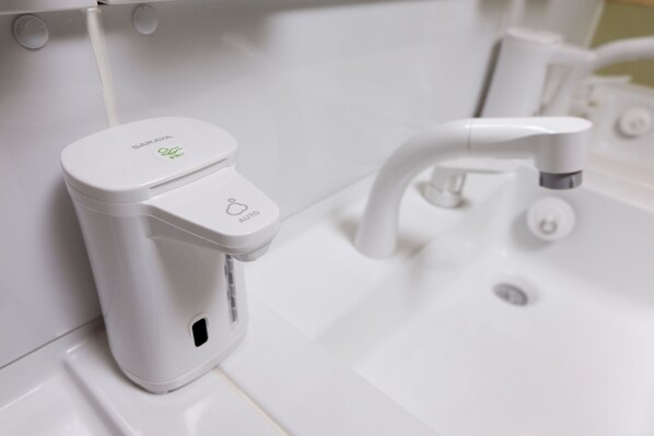 Une salle de bain moderne avec un lavabo blanc, un robinet et un distributeur de savon.