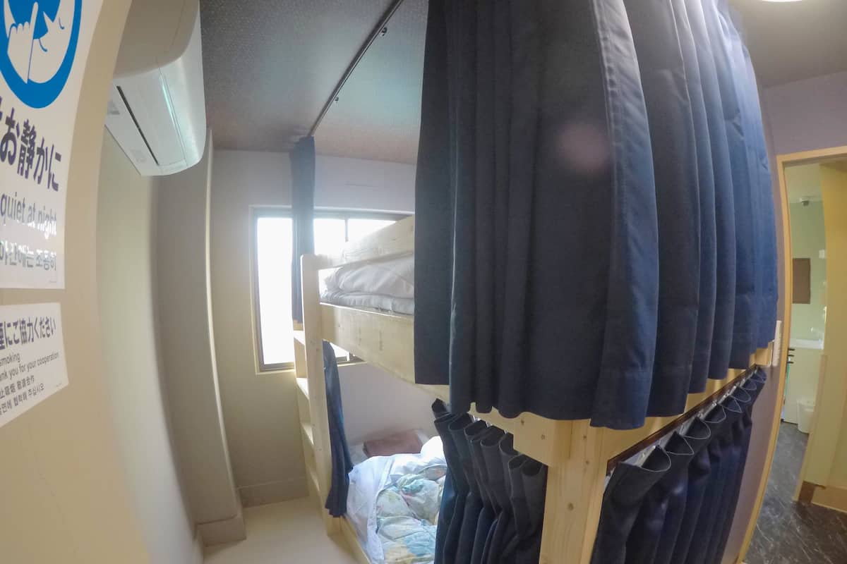 Un dormitorio con literas, una ventana y una barra para cortinas con varias cortinas.