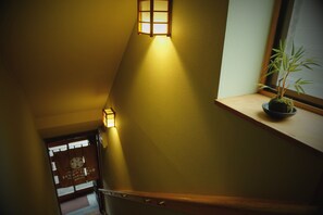 Un escalier avec des rampes en bois et un pot de fleurs posé sur une étagère.