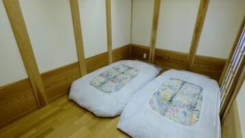 A room with two beds, wooden flooring, and a simple, functional design.