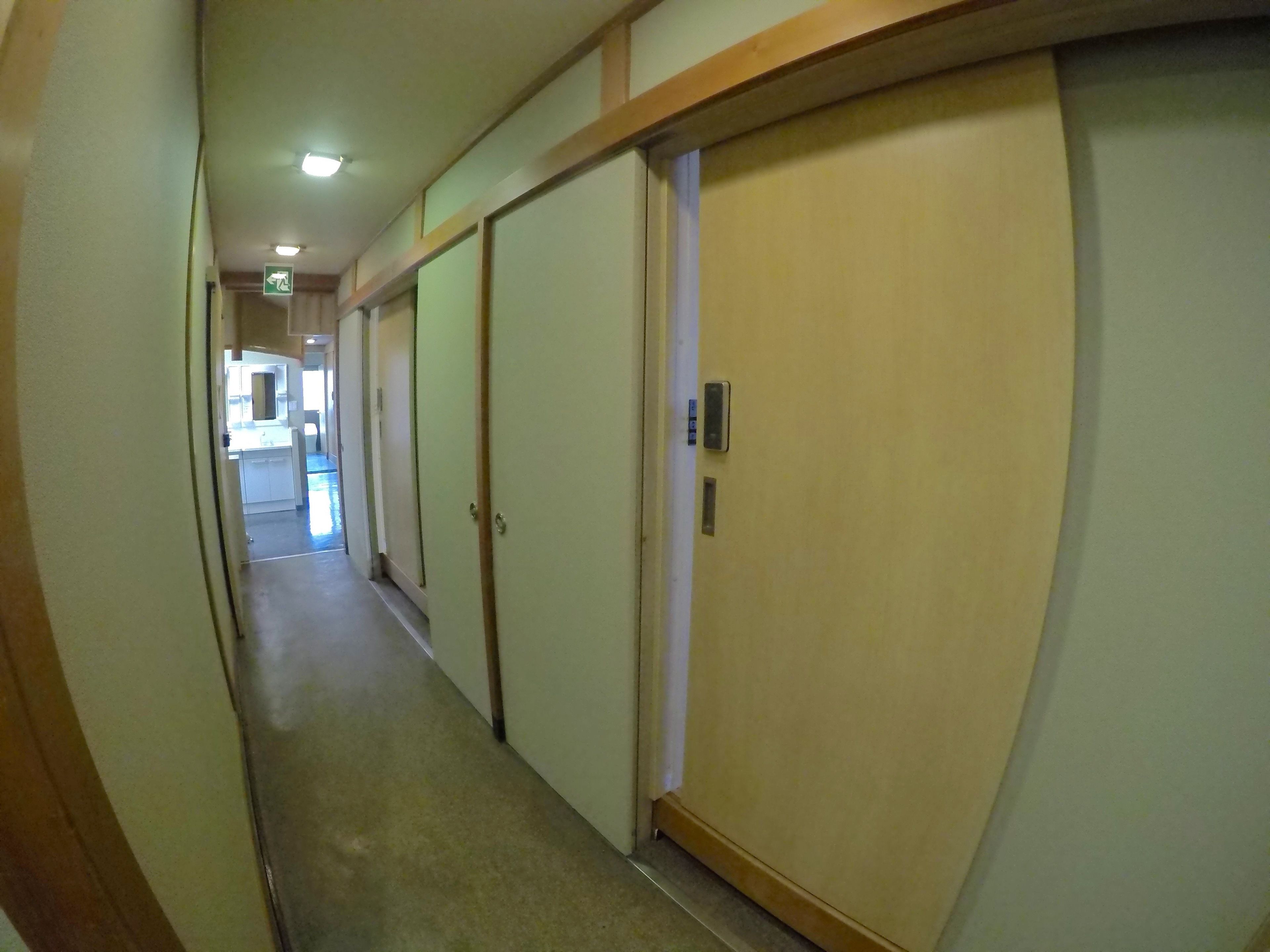A narrow hallway with doors on both sides, leading to rooms.