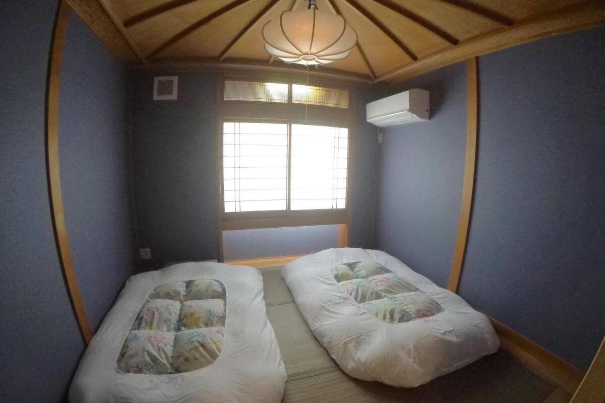 Una habitación pequeña con dos camas, una ventana y un ventilador de techo.